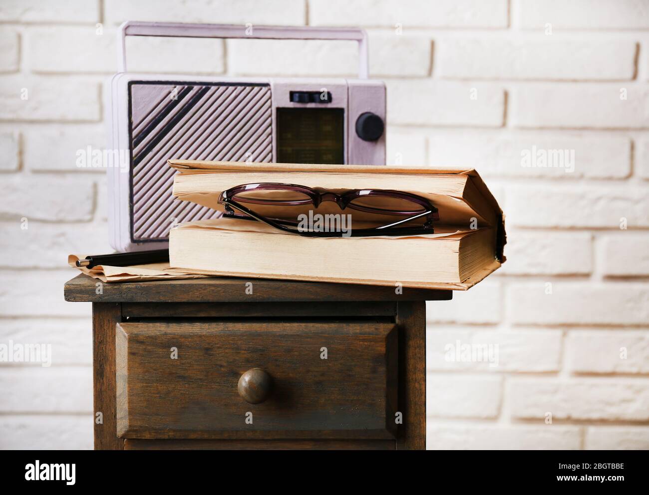 Retro-Radio, Buch und Gläser auf dem Tisch im Zimmer Stockfoto