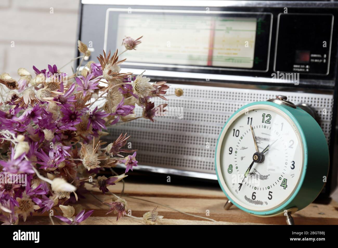 Retro-Radio, Uhr und Blumen auf dem Tisch im Zimmer Stockfoto