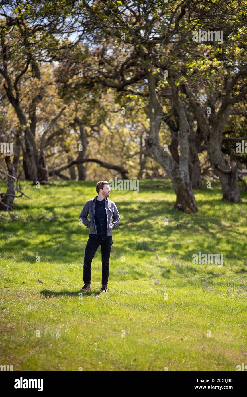 Ganzkörper-Porträt des jungen Mannes lässig im Freien mit Bäumen gekleidet Stockfoto