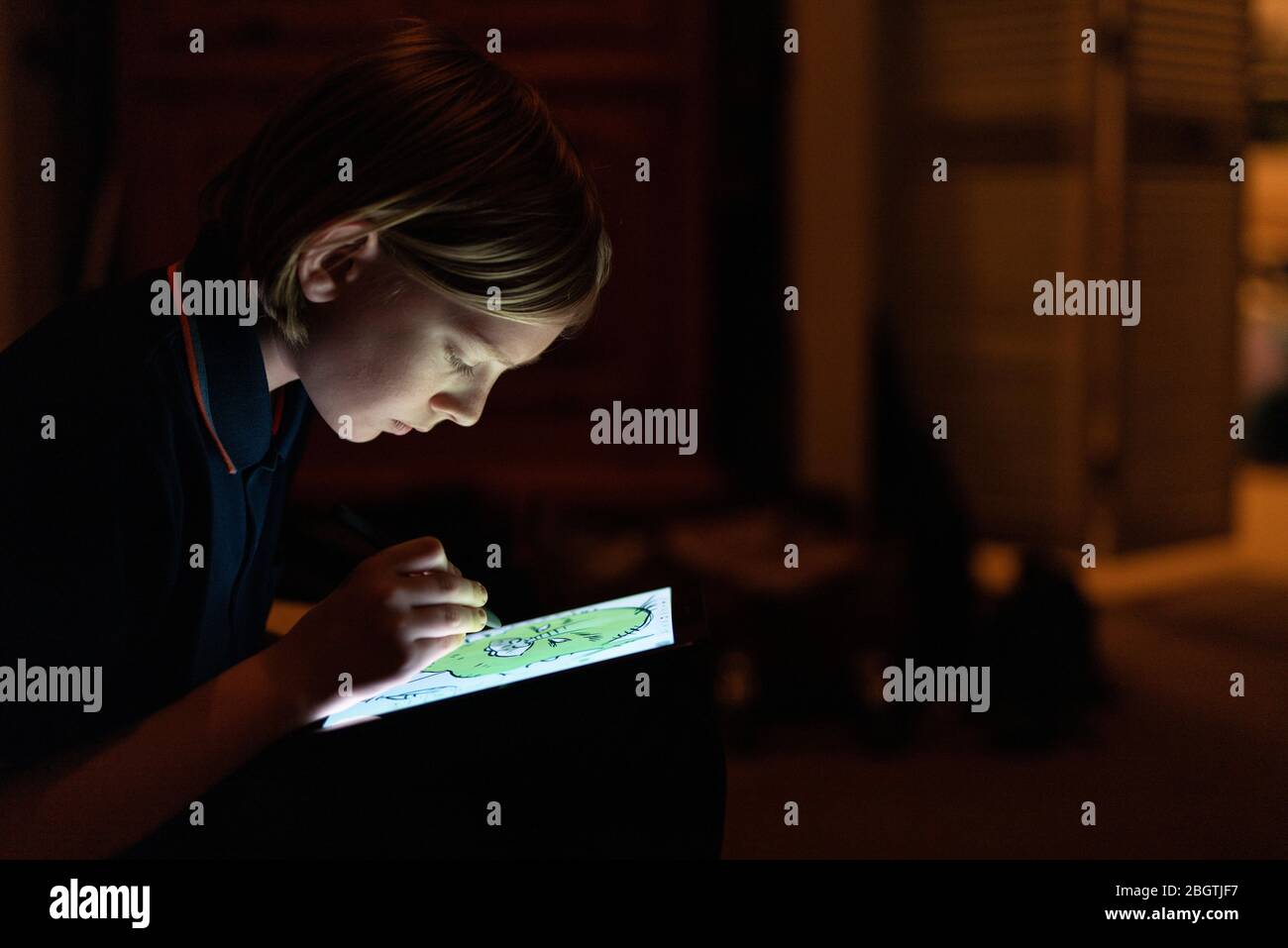 Profil der Tween-Zeichnung mit Stift auf Tablet in geschlossenen Räumen schwach beleuchtet Stockfoto