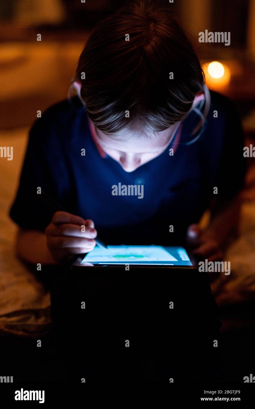 Teenager Zeichnung auf Tablet mit hellen Bildschirm und Stift bei schwachem Licht Stockfoto