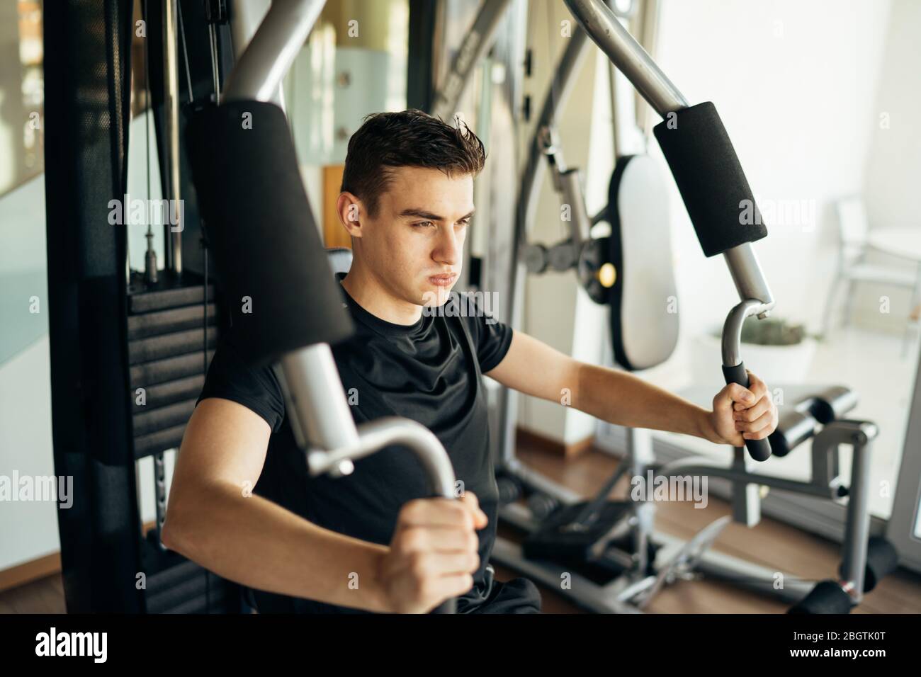 Junger Mann tun Fitness-Übungen auf Home Gym Brust drücken Maschine.Making eine Anstrengung und Training für fit getönten Sommer Körper shape.Home Workout.Weight lo Stockfoto
