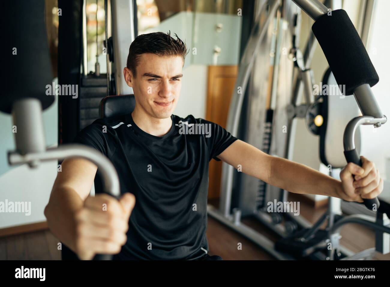 Junger Mann tun Fitness-Übungen auf Home Gym Brust drücken Maschine.Making eine Anstrengung und Training für fit getönten Sommer Körper shape.Home Workout.Weight lo Stockfoto