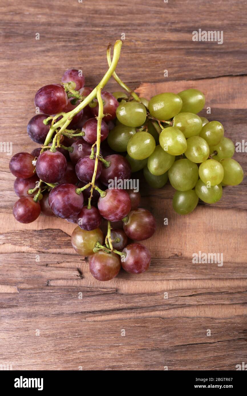 Trauben verschiedener Arten von Trauben auf Holzhintergrund Stockfoto