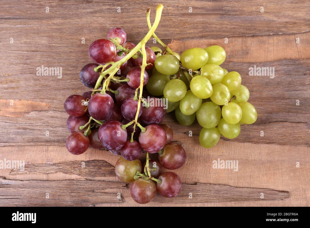 Trauben verschiedener Arten von Trauben auf Holzhintergrund Stockfoto