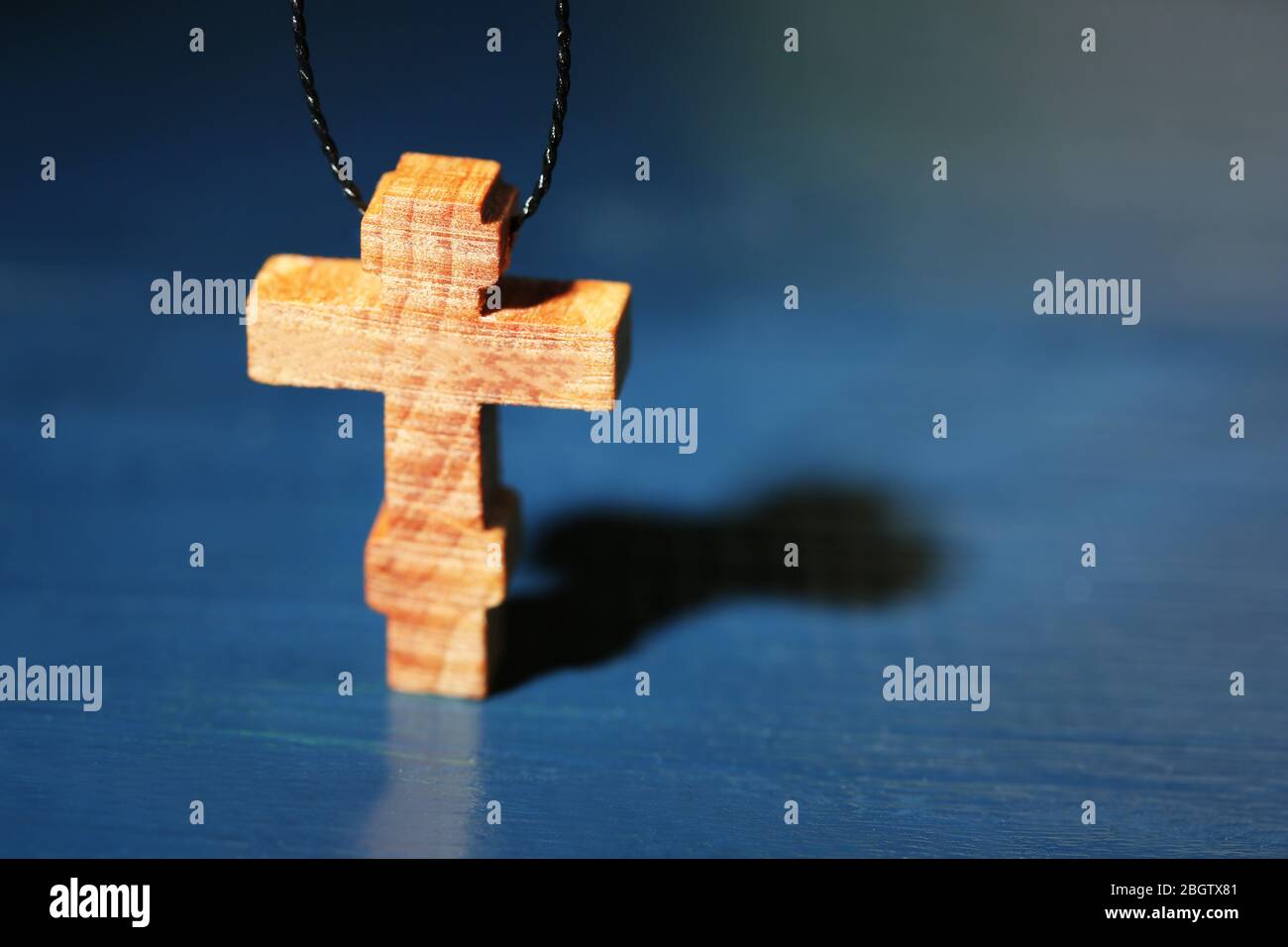 Holzkreuz mit tiefen Schatten auf Holzhintergrund Stockfoto