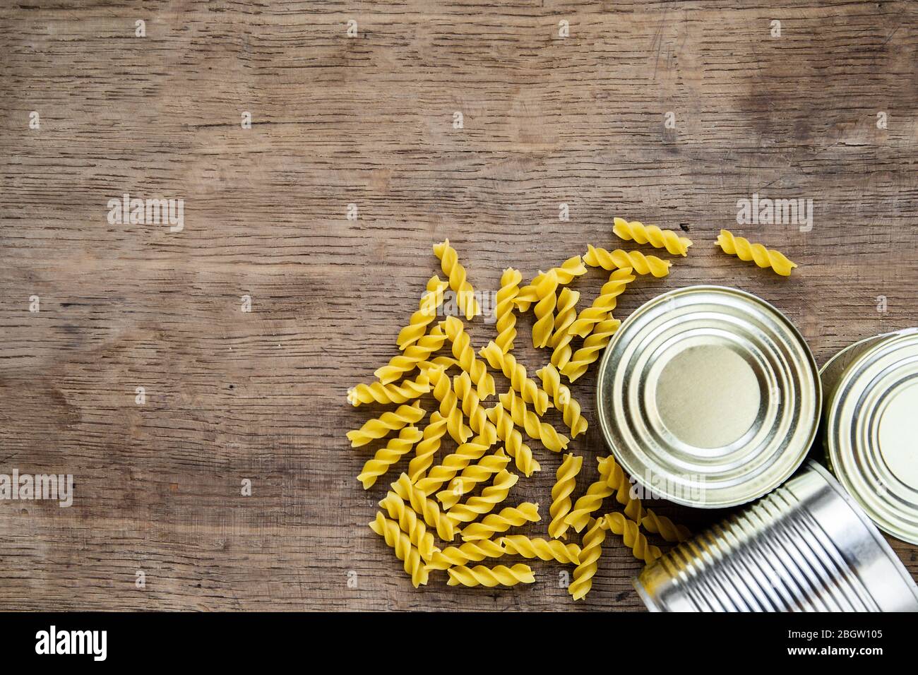 Vorrat für Coronavirus Quarantäne Isolationsperiode auf Holzhintergrund. Verschiedene Lebensmittel in Aluminiumdosen, Reis, Pasta. Lieferung von Lebensmitteln, Spende Stockfoto