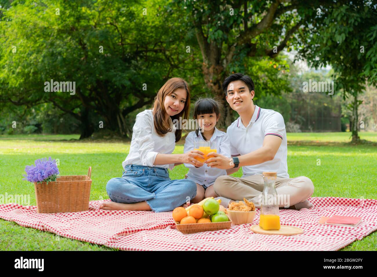 Asiatische Teenager Familie glücklich Urlaub Picknick Moment im Park mit Vater, Mutter und Tochter mit Orangensaft Glas und Lächeln glücklich verbringen vacatio Stockfoto