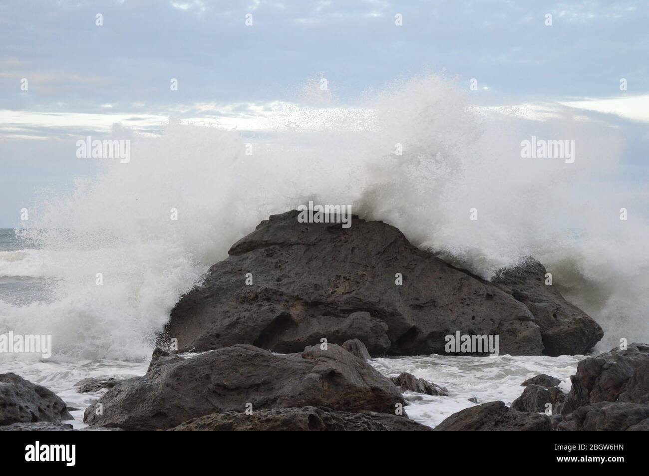 Wellen schlagen auf einem Felsen am Mount Maunganui Strand Stockfoto