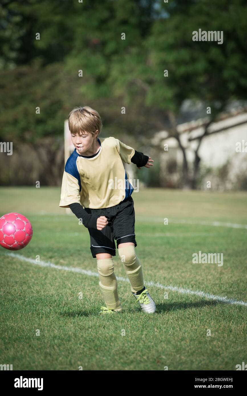 Porträt eines Jungen Fußball spielen, bereit, den Ball zu treten Stockfoto