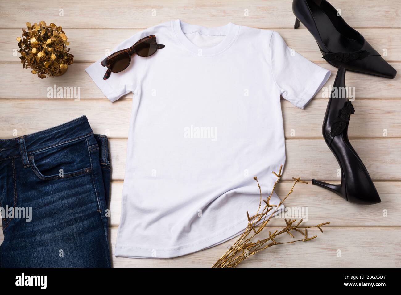Weißes Baumwoll-T-Shirt Mockup mit schwarzen High Heels spitz Zehen Frauen Pumps und goldenen Pflanzen. Design T-Shirt Vorlage, T-Print Präsentation Mock up Stockfoto