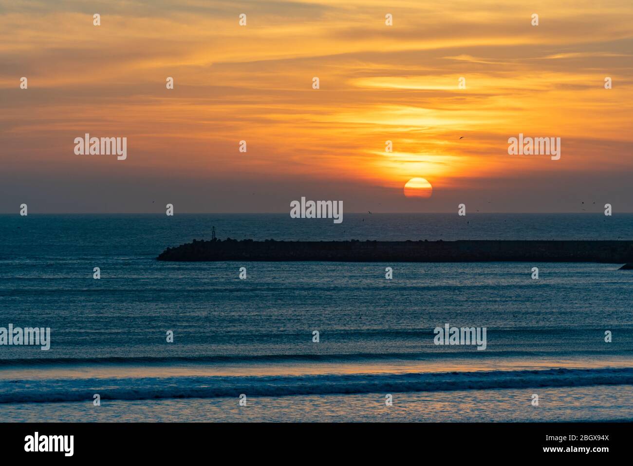 Sonnenuntergang am Strand in Essaouira Marokko in der Nähe des Horizonts mit Wellen Stockfoto