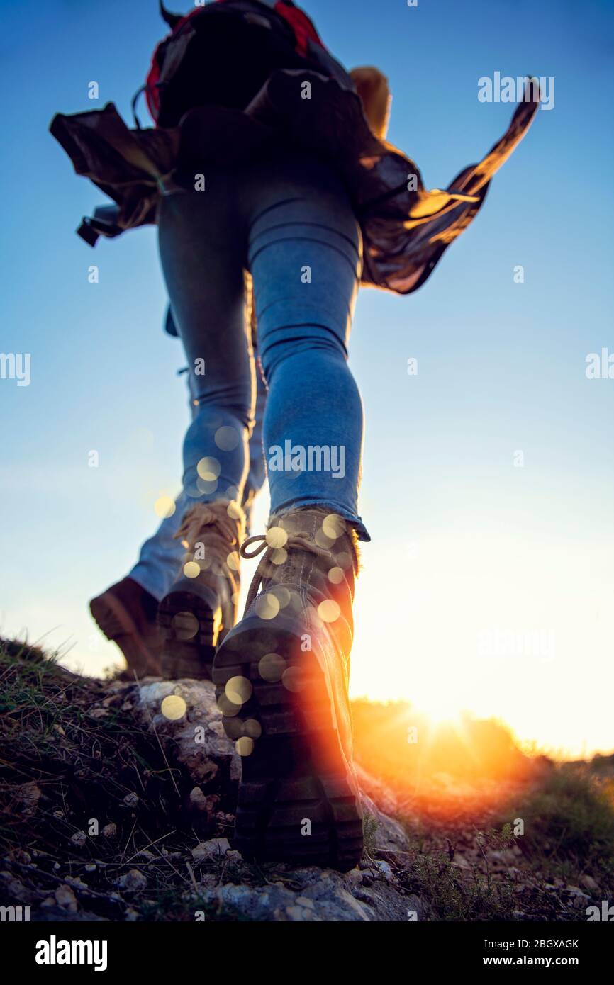 Ein Touristenpaar mit Wanderschuhen geht einen grasbewachsenen Hügel in den Alpen hinauf. Stockfoto