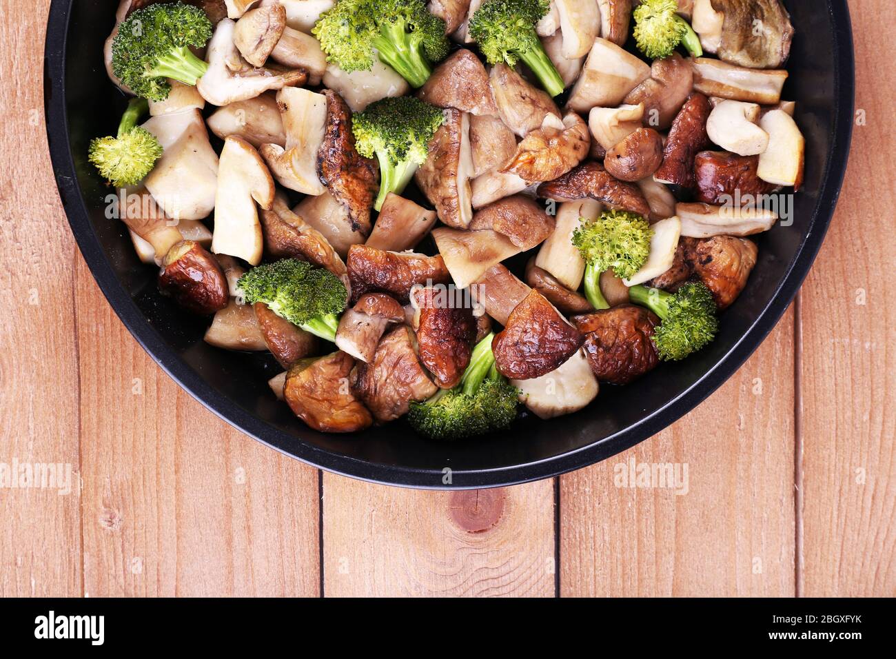 Geschmorte Wildpilze mit Gemüse und Gewürzen in der Pfanne auf dem Tisch Stockfoto