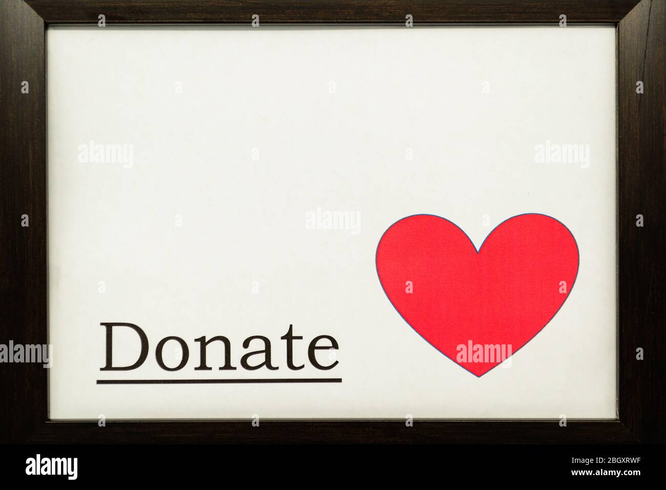 Das Wort 'Donate' auf weißem Hintergrund neben einem roten Herz Stockfoto