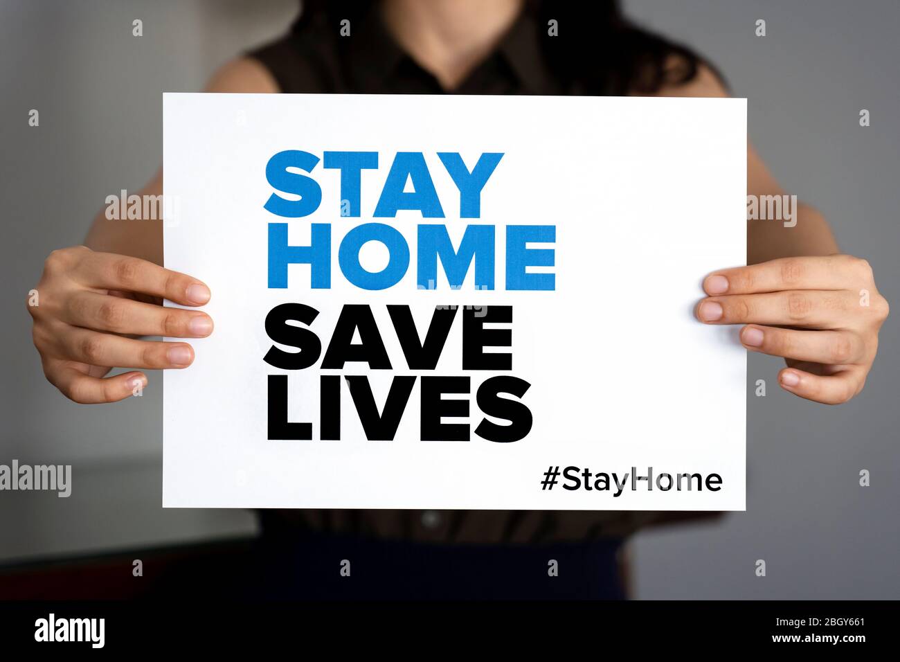 Frau mit dem Schild 'Stay Home Save Lives', globale Botschaft inmitten der Coronavirus-Krise. Quarantäne-Nachricht auf der ganzen Welt zur Bekämpfung der COVID-19-Pandemie. Stockfoto