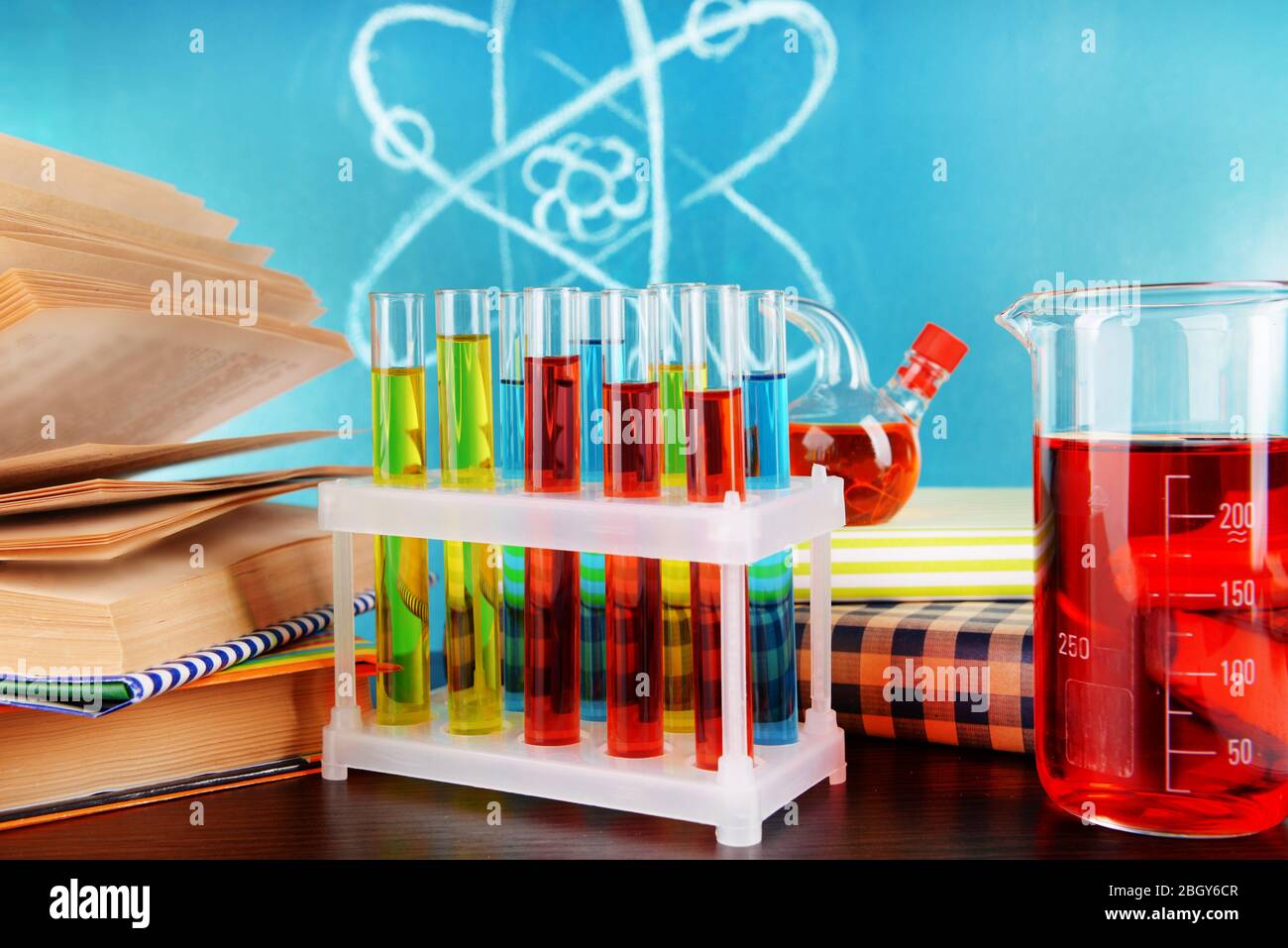 Glaswaren mit chemischen Substanzen auf dem Schreibtisch, auf grünem Tafelgrund Stockfoto