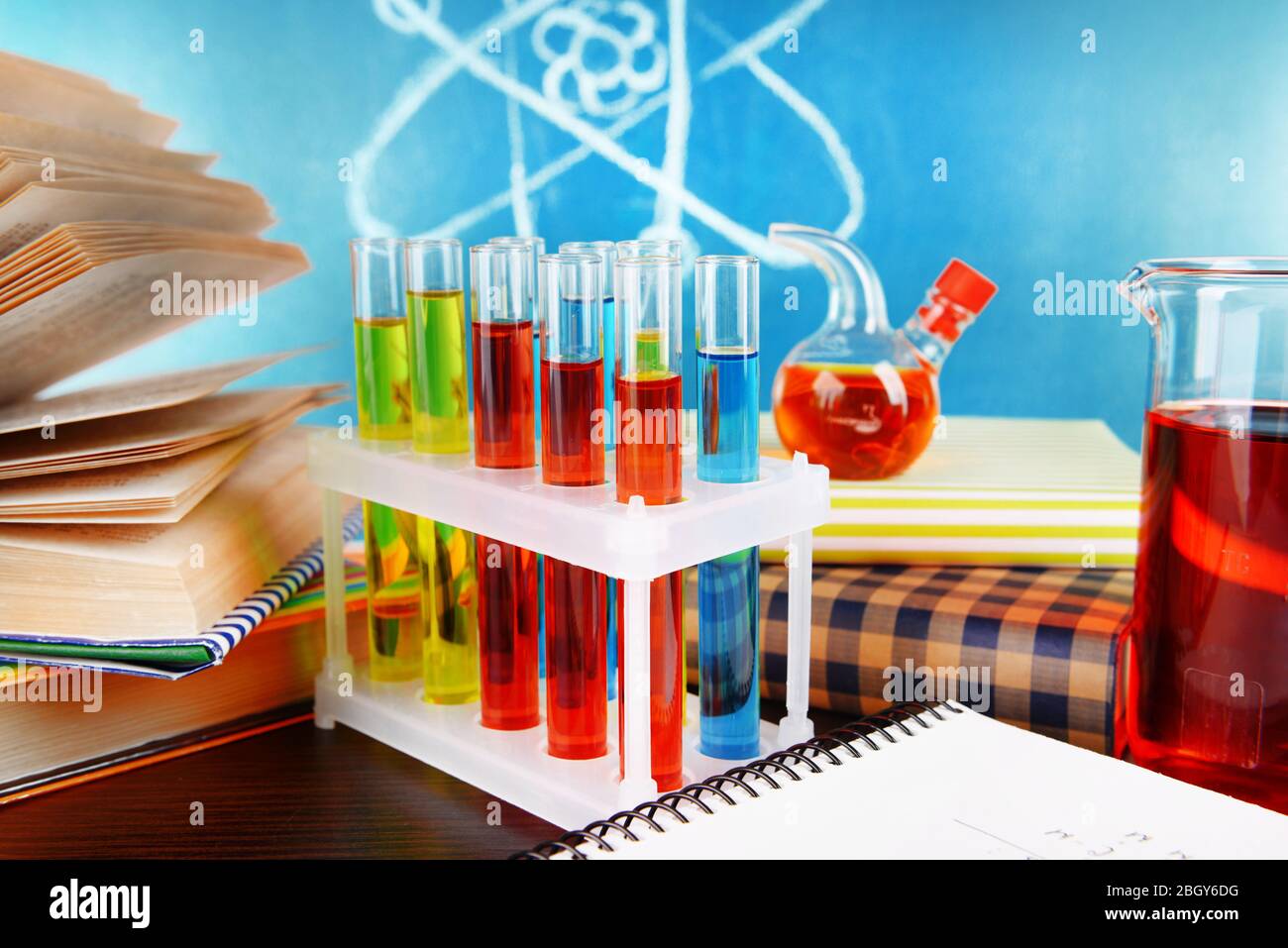 Glaswaren mit chemischen Substanzen auf dem Schreibtisch, auf grünem Tafelgrund Stockfoto