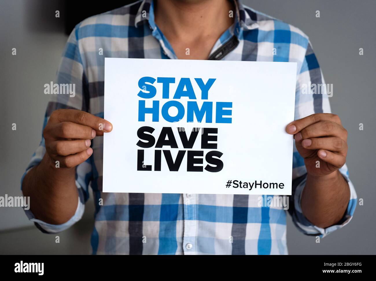 Mann mit dem Zeichen 'Stay Home Save Lives' globale Botschaft inmitten der Coronavirus-Krise. Quarantäne-Nachricht auf der ganzen Welt zur Bekämpfung der COVID-19-Pandemie. Stockfoto