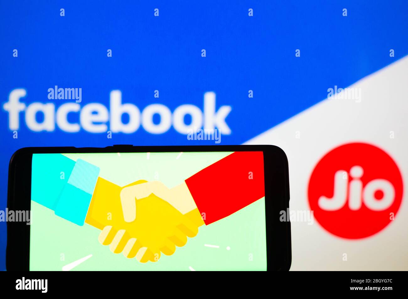 Handy mit Handshake-Bildschirm und facebook und jio im Hintergrund Stockfoto