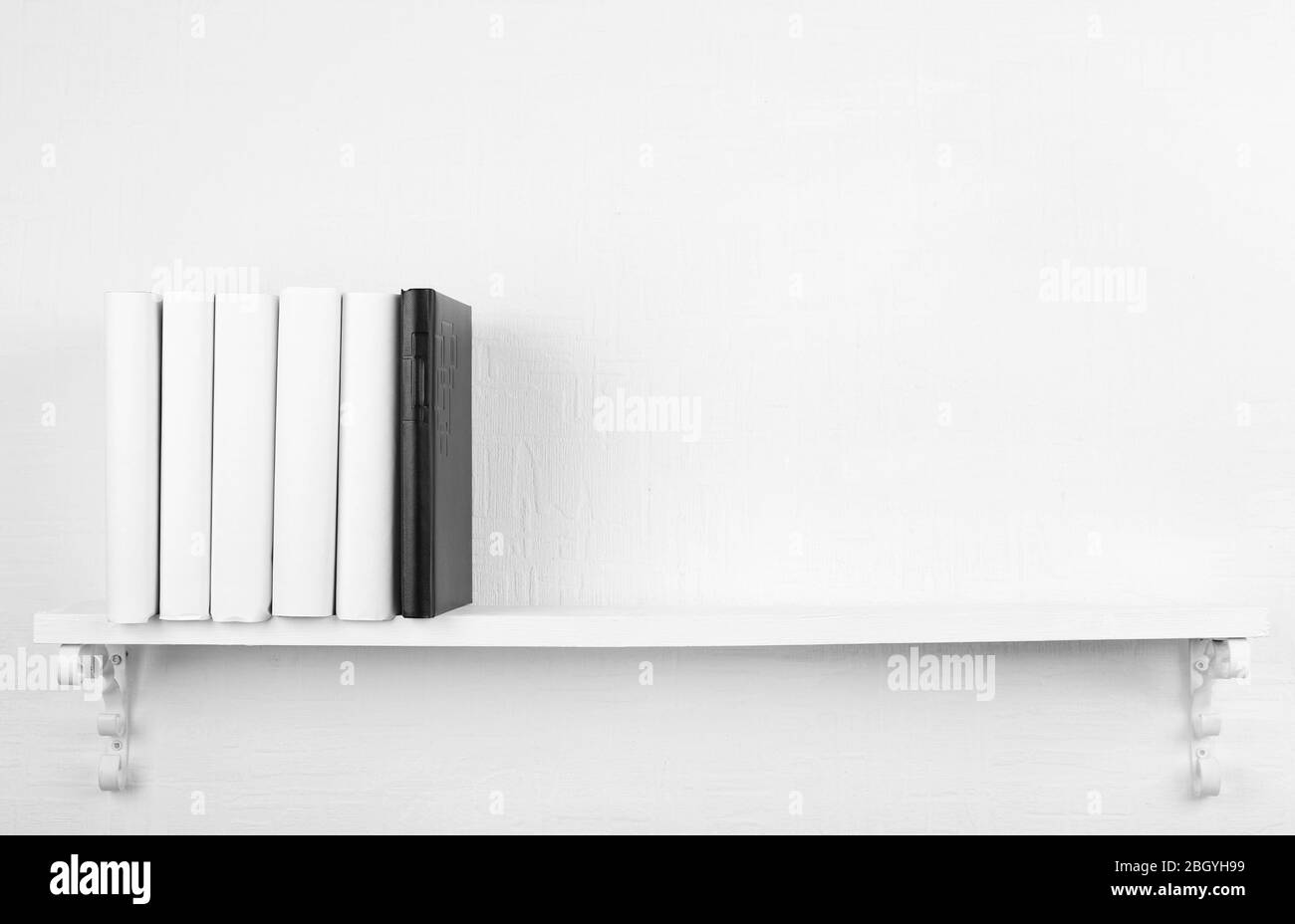 Leere Bücher mit schwarzem auf Bücherregal auf weißem Wandhintergrund Stockfoto
