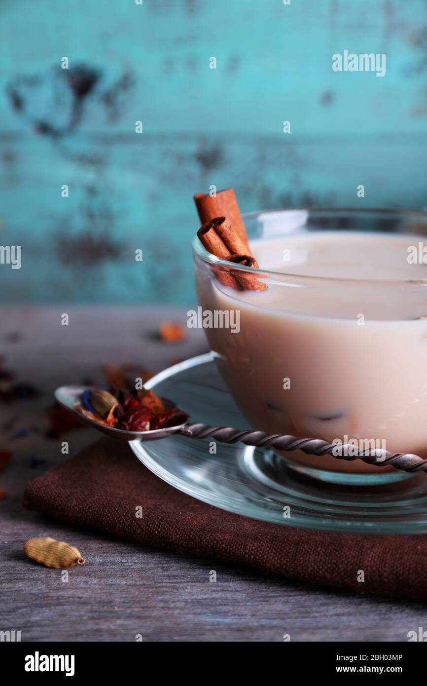 Schwarzer Tee mit Milch und Klumpen Zucker und Gewürze in Glaswaren auf farbigen Holzplanken