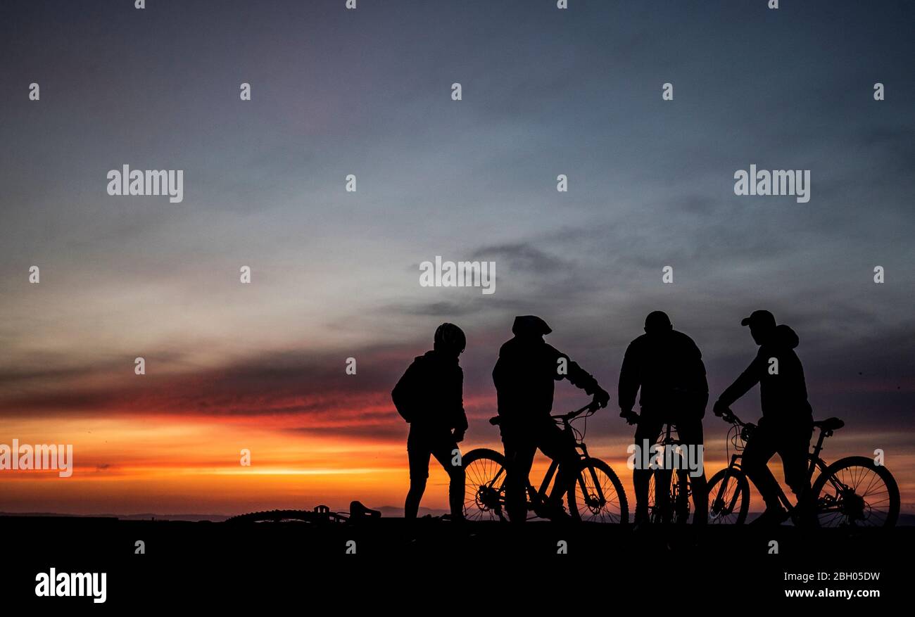 Radfahrer beobachten den Sonnenuntergang im Hafen von Newhaven in Edinburgh. Stockfoto