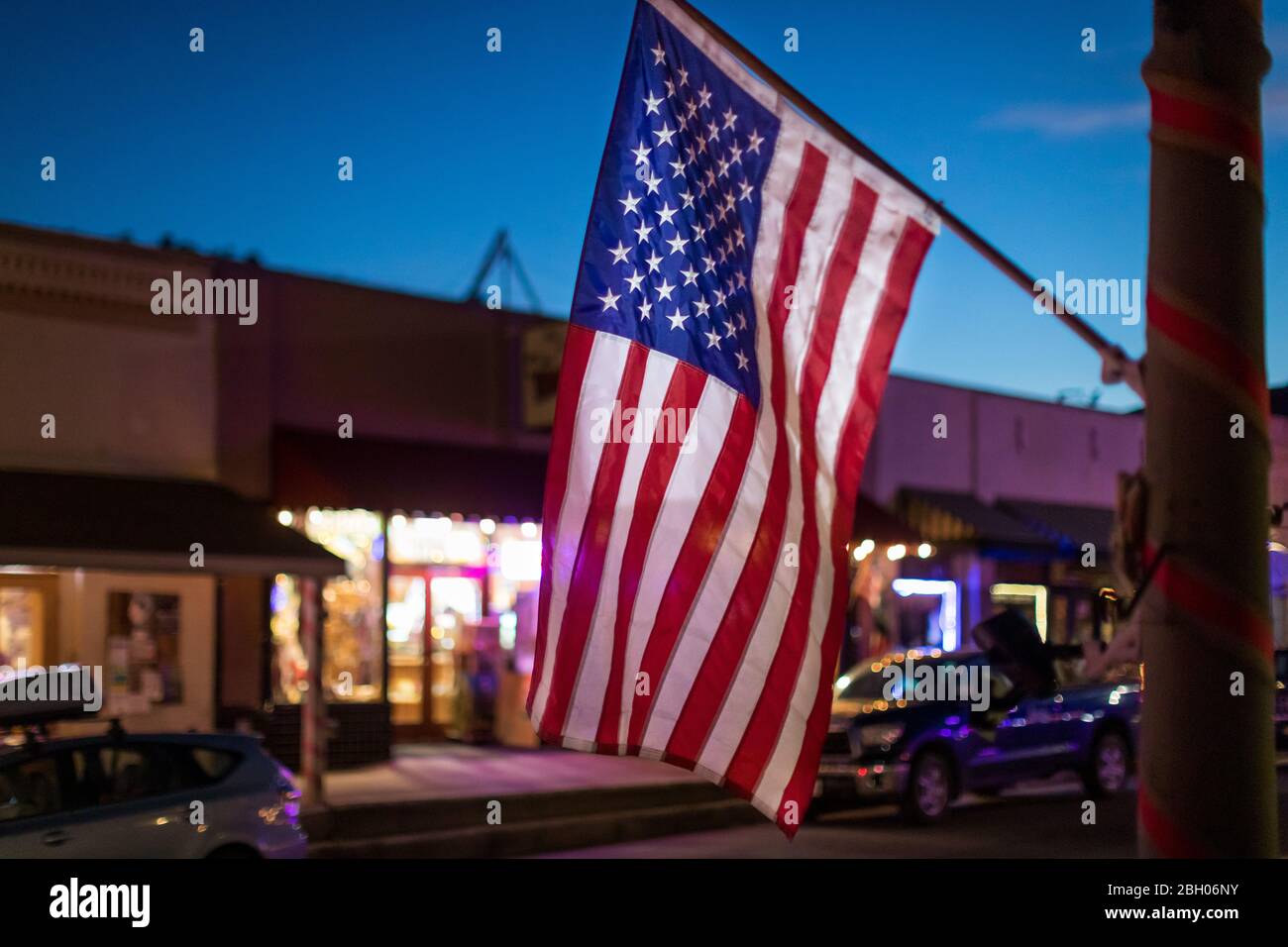 In der Abenddämmerung hängt eine amerikanische Flagge vor einem Geschäft in einem kleinen südwestlichen Dorf Stockfoto