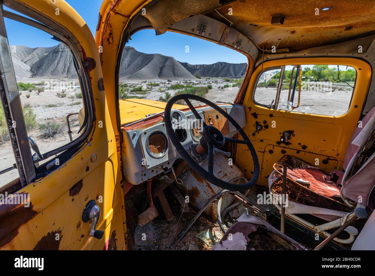 Der Fahrersitz eines gelb rostigen verlassenen Zementmischers LKW in einem Kiesgrube Stockfoto
