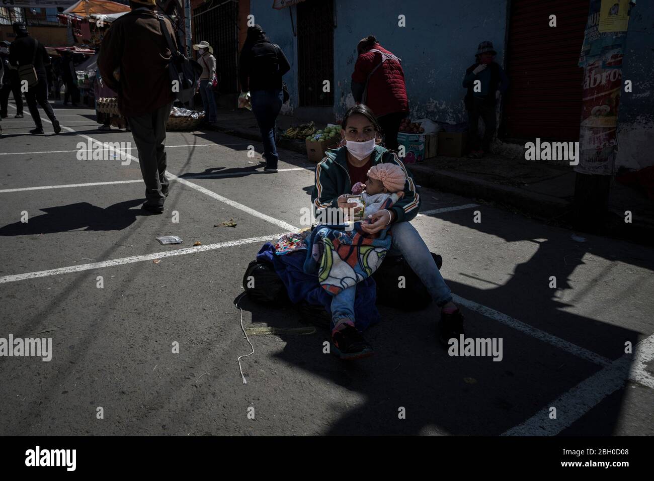 La Paz, Bolivien. April 2020. Eine Zugewanderin aus Venezuela sitzt mit ihrem Kind auf dem Boden eines Straßenmarktes. Nur einmal pro Woche darf ein Mitglied pro Familie zwischen 7 und 12 Uhr auf den Märkten Lebensmittel kaufen. Quelle: Marcelo Perez del Carpio/dpa/Alamy Live News Stockfoto