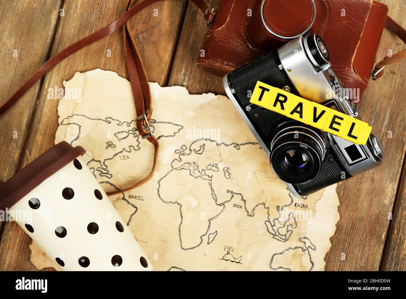 Retro-Kamera auf Weltkarte mit Wort Reisen auf Holztisch Hintergrund Stockfoto