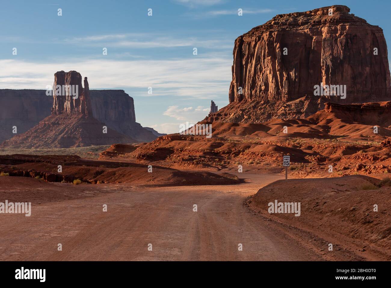 Eine Schotterstraße schlängelt sich durch das Monument Valley, mit zwei riesigen roten Sandsteinformationen im Hintergrund Stockfoto