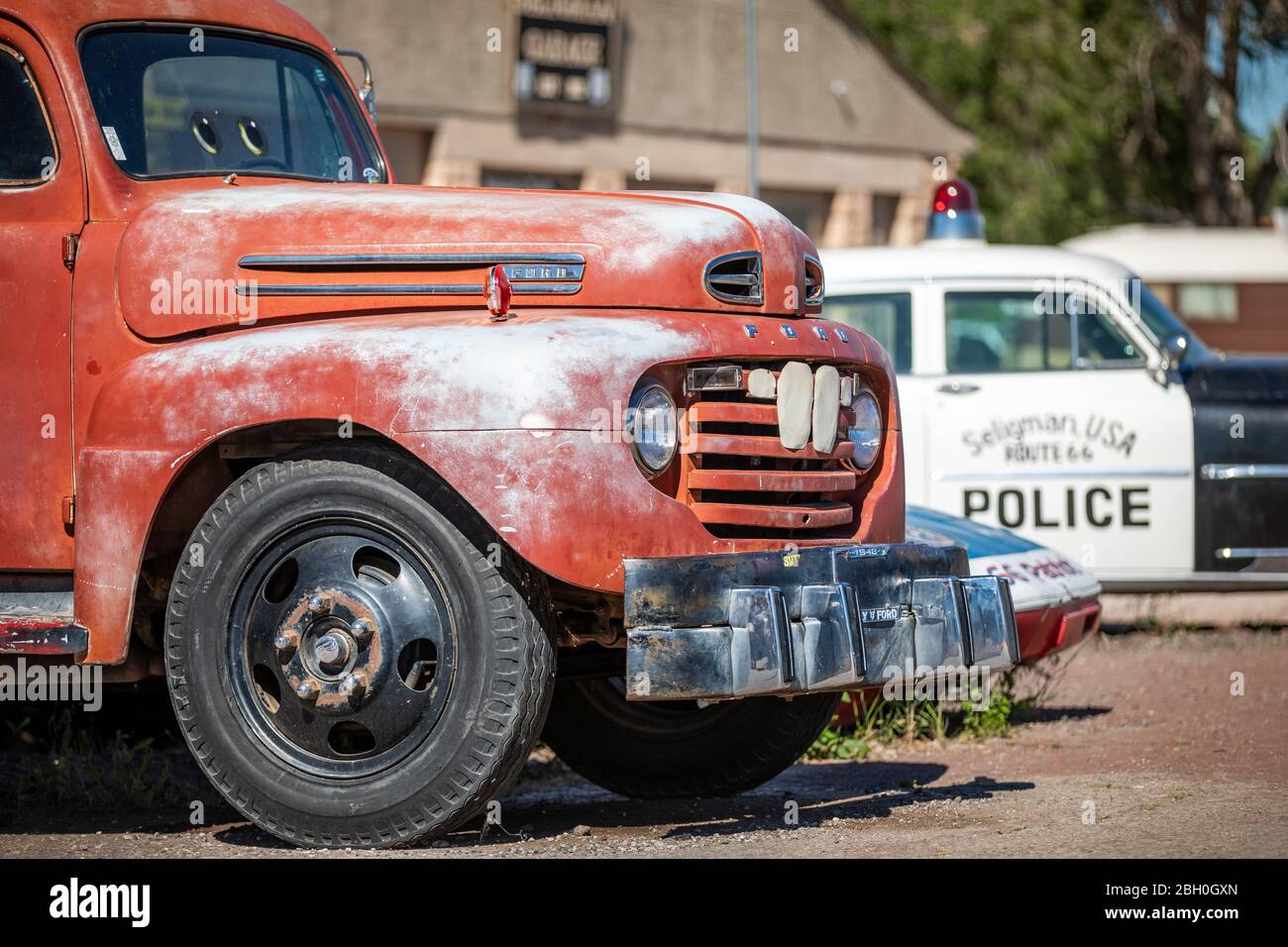 Nahaufnahme eines roten Vintage-Abschleppwagens mit einem Oldtimer-Polizeiauto im Hintergrund Stockfoto