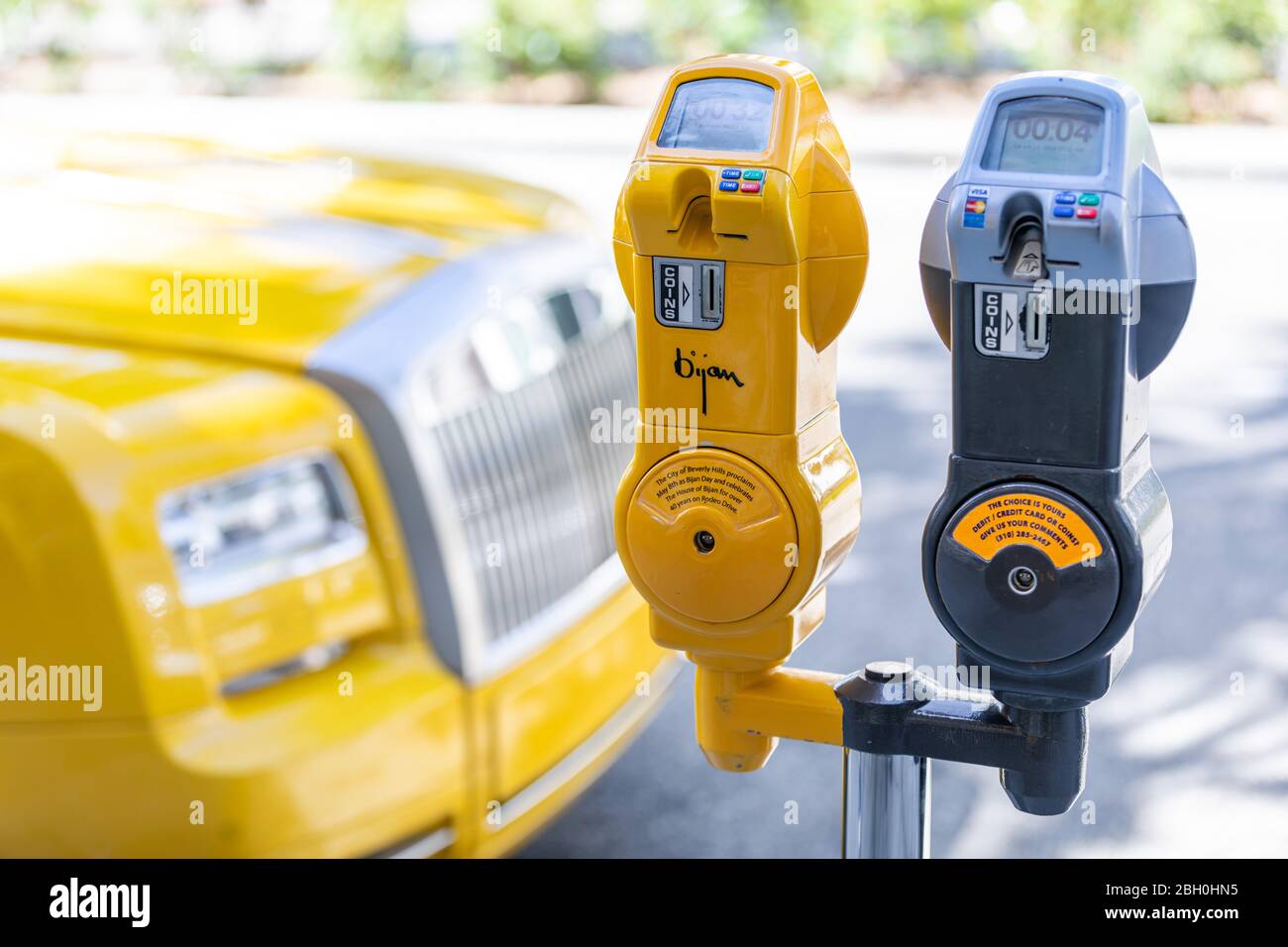 Nahaufnahme des gelben Parkzählers, signiert von Bijan in Rodeo Drive, mit seinem gelben Rolls Royce im Hintergrund Stockfoto