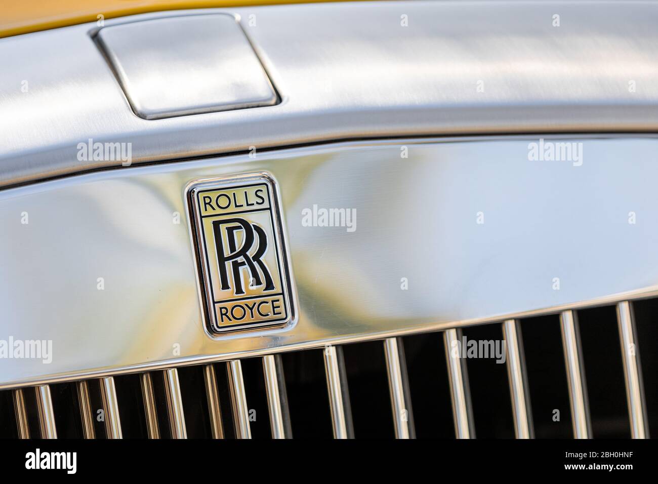 Ikonische Nahaufnahme des Chrom-Markennamens und Kühlergrill eines gelben Rolls Royce Auto Stockfoto