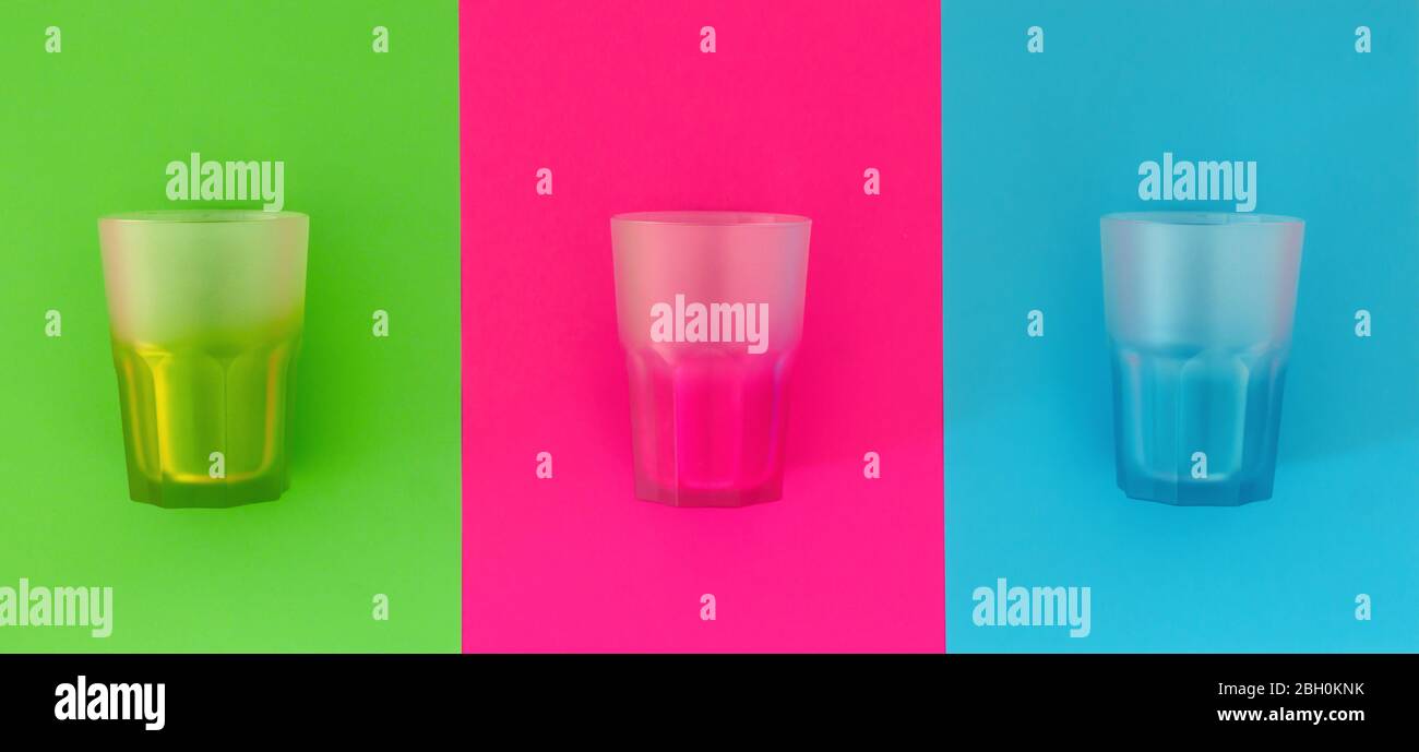 Angeordnet leere transparente mehrfarbige Trinkgläser auf bunten Hintergrund minimalistischen Kopieraum Stockfoto