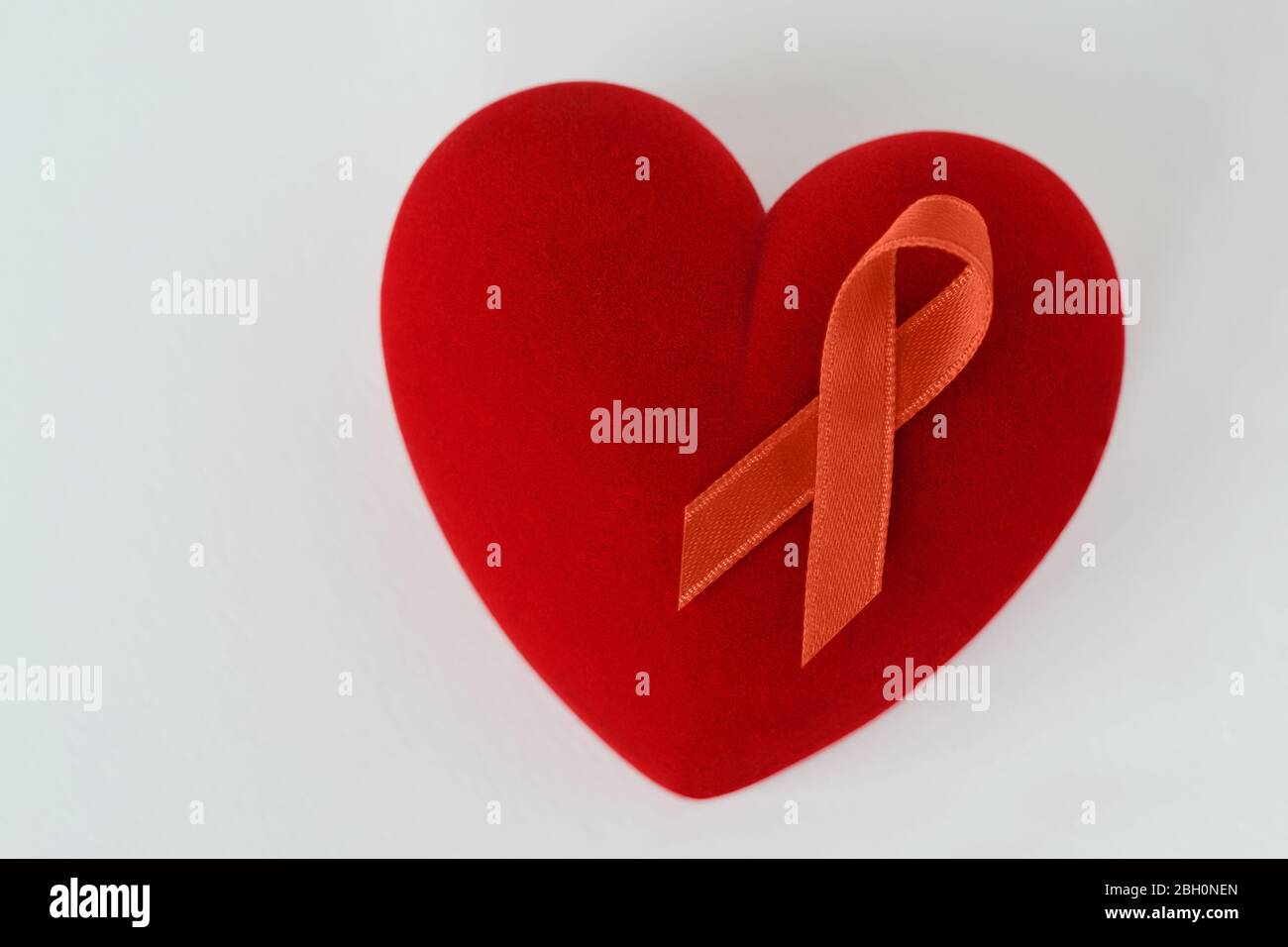 Herz mit orangefarbenem Band auf weißem Hintergrund - Konzept der Leukämie Bewusstsein, Nierenkrebs Assoziation, Multiple Sklerose und Tiermissbrauch Stockfoto