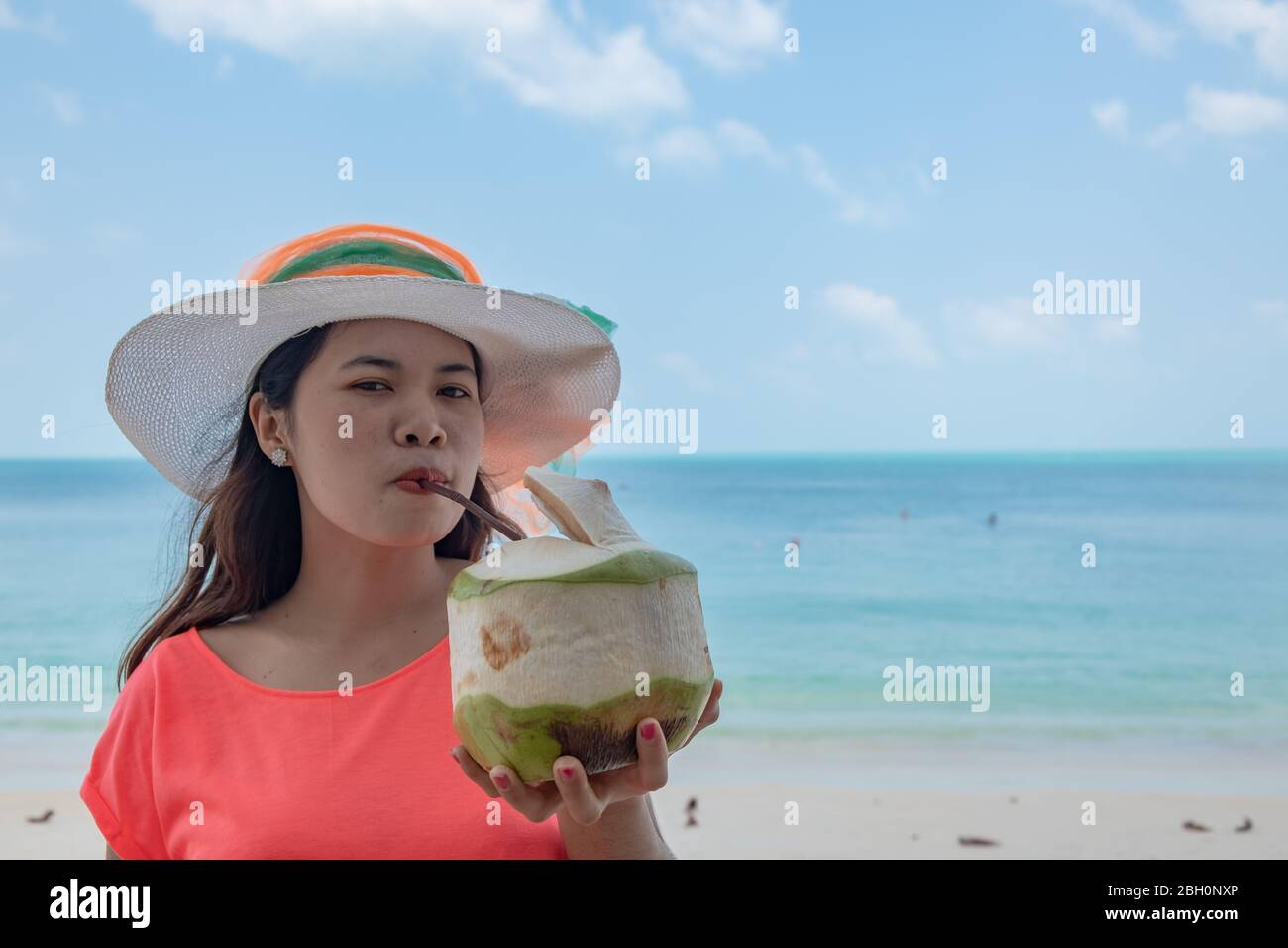 Schöne asiatische Mädchen am Strand. Thai Dame, trinken Kokoswasser am türkisfarbenen Meer während Urlaub Reise im Freien am natürlichen Ozean auf Insel, Thailand Stockfoto