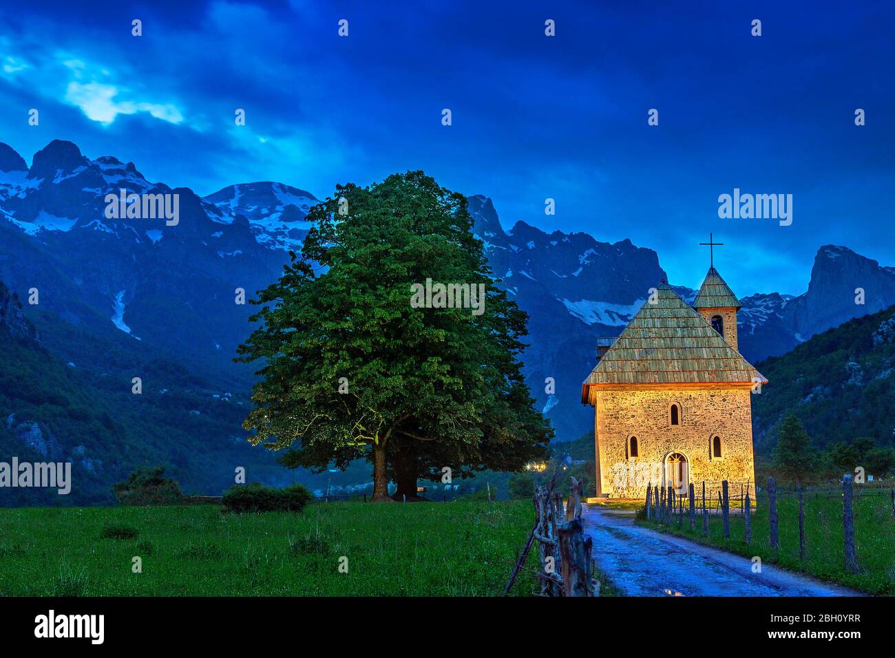 Kirche im Dorf Thethi und schneebedeckten Bergen, in der Dämmerung, am Theth Tal, Albanien Stockfoto