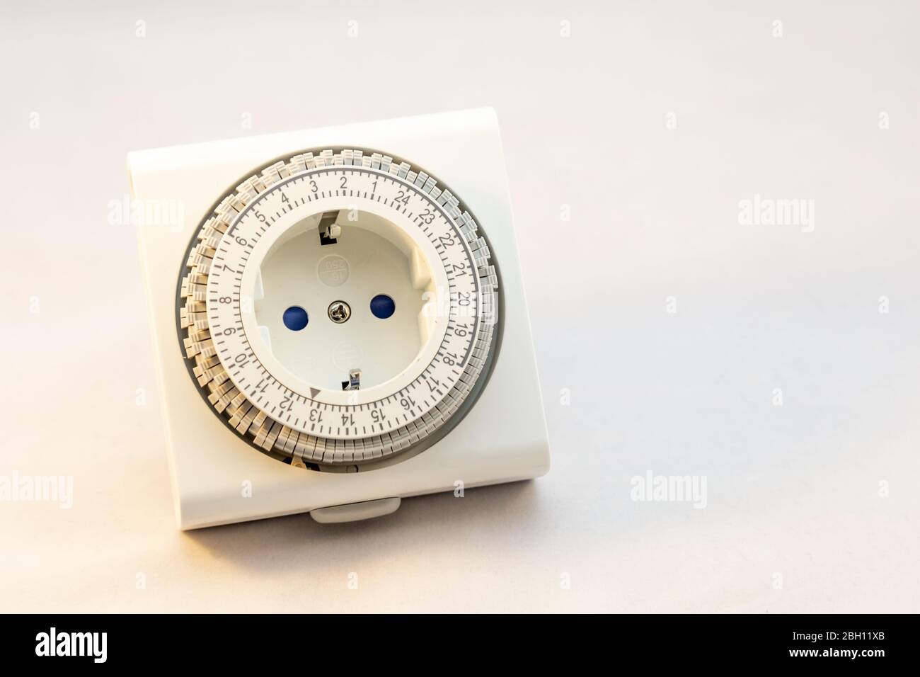 Analoger Timer-Schalter, um Ihr Licht auf einen bestimmten Moment auf weißem Hintergrund einzuschalten oder das Gerät einzuschalten Stockfoto