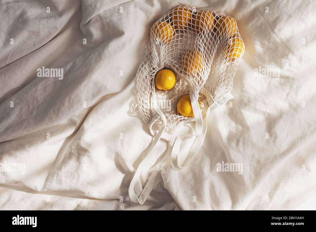 Baumwolltasche mit Zitronen auf dem Bett. Stockfoto