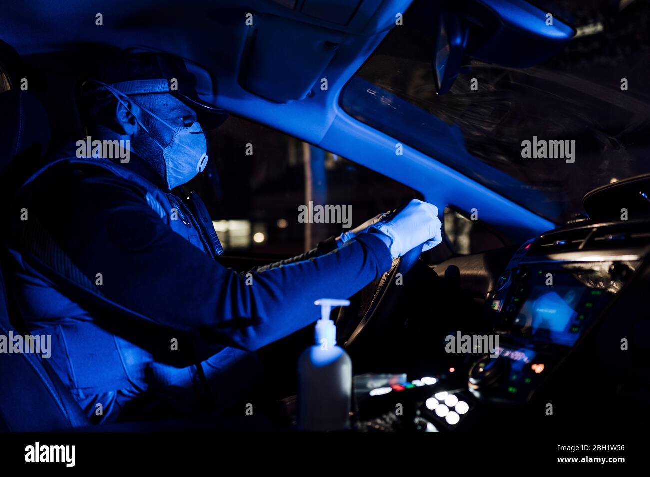 Polizist trägt Maske und Schutzhandschuhe während der Notmission in der Nacht Stockfoto