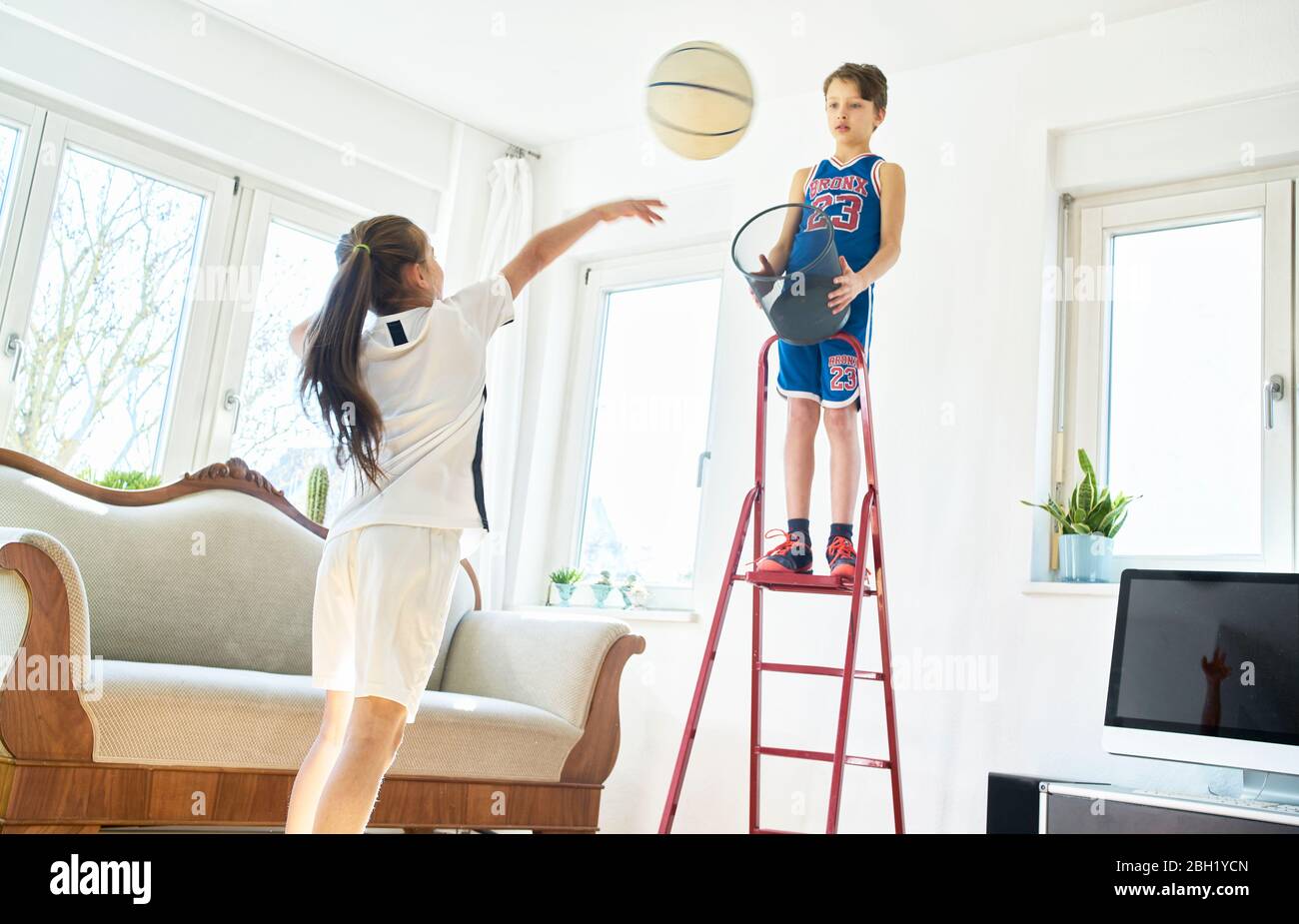 Junge und Mädchen spielen Basketball im Wohnzimmer Stockfoto