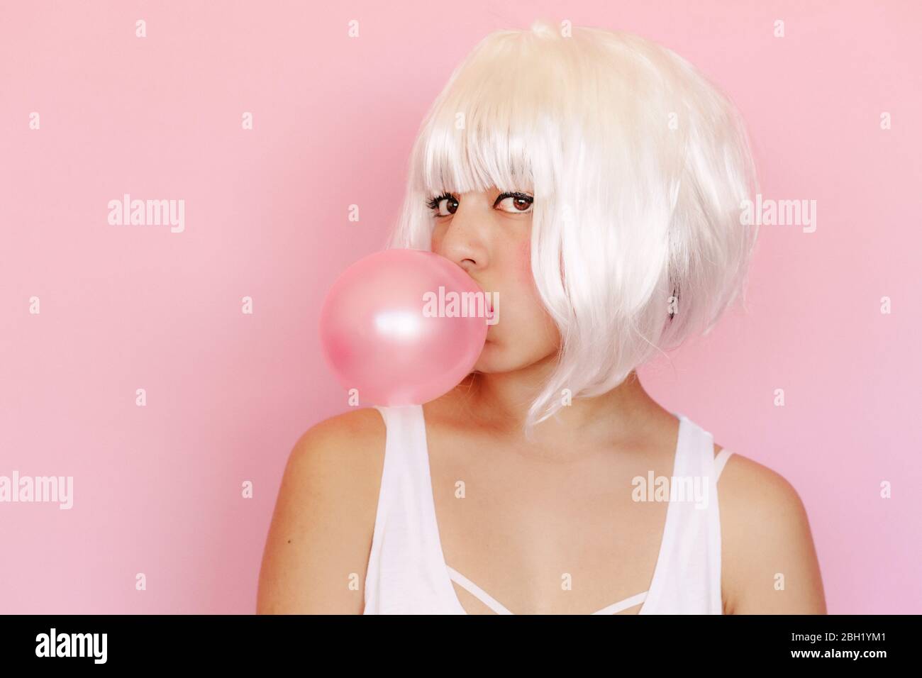 Porträt einer jungen Frau mit rosa Kaugummi Blase vor rosa Hintergrund Stockfoto