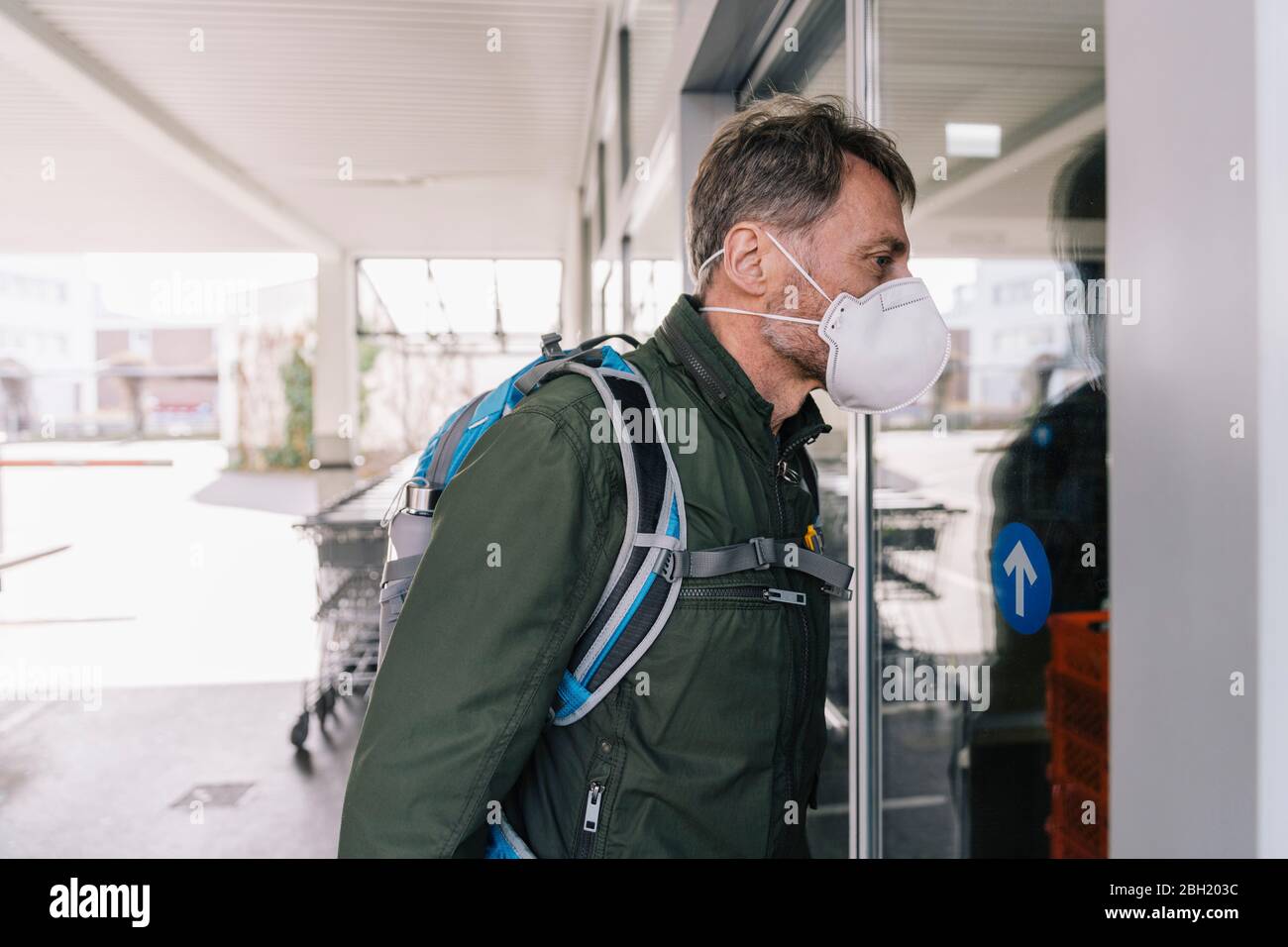 Mann mit Maske, der in den Supermarkt schaut Stockfoto