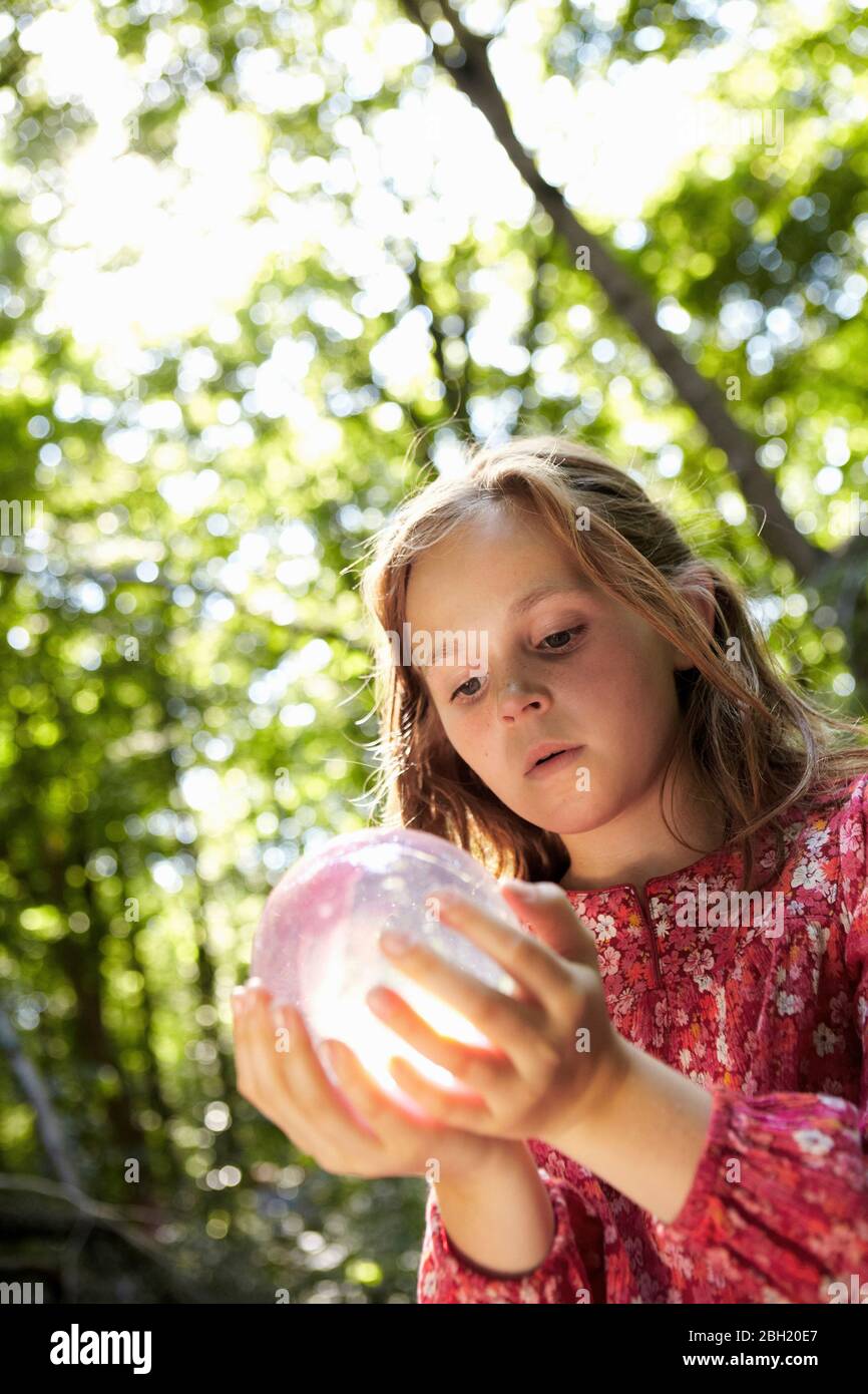 Mädchen hält Kristallkugel im Wald Stockfoto