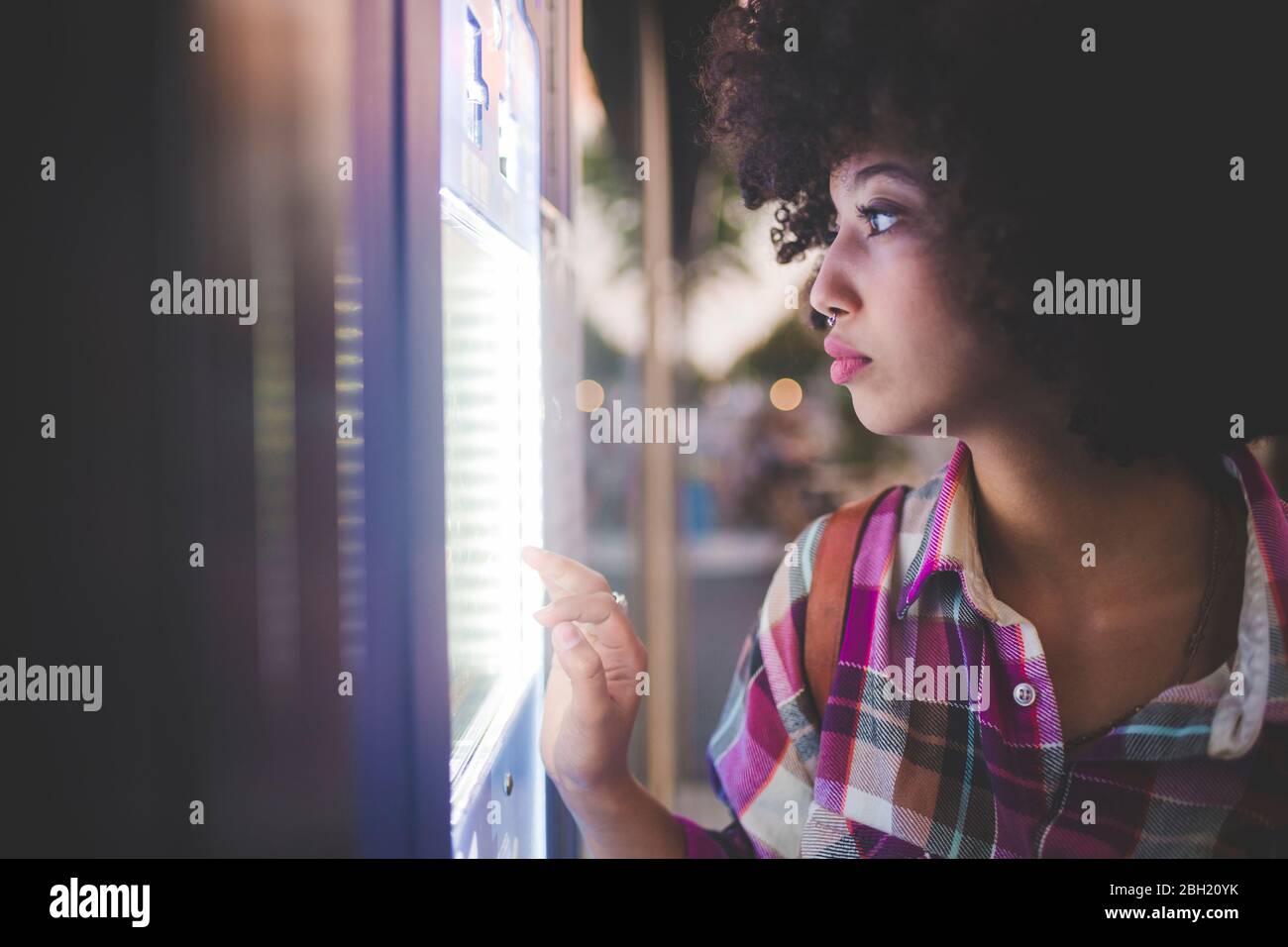 Junge Frau mit Afro-Frisur mit Touchscreen-Automaten in der Stadt Stockfoto
