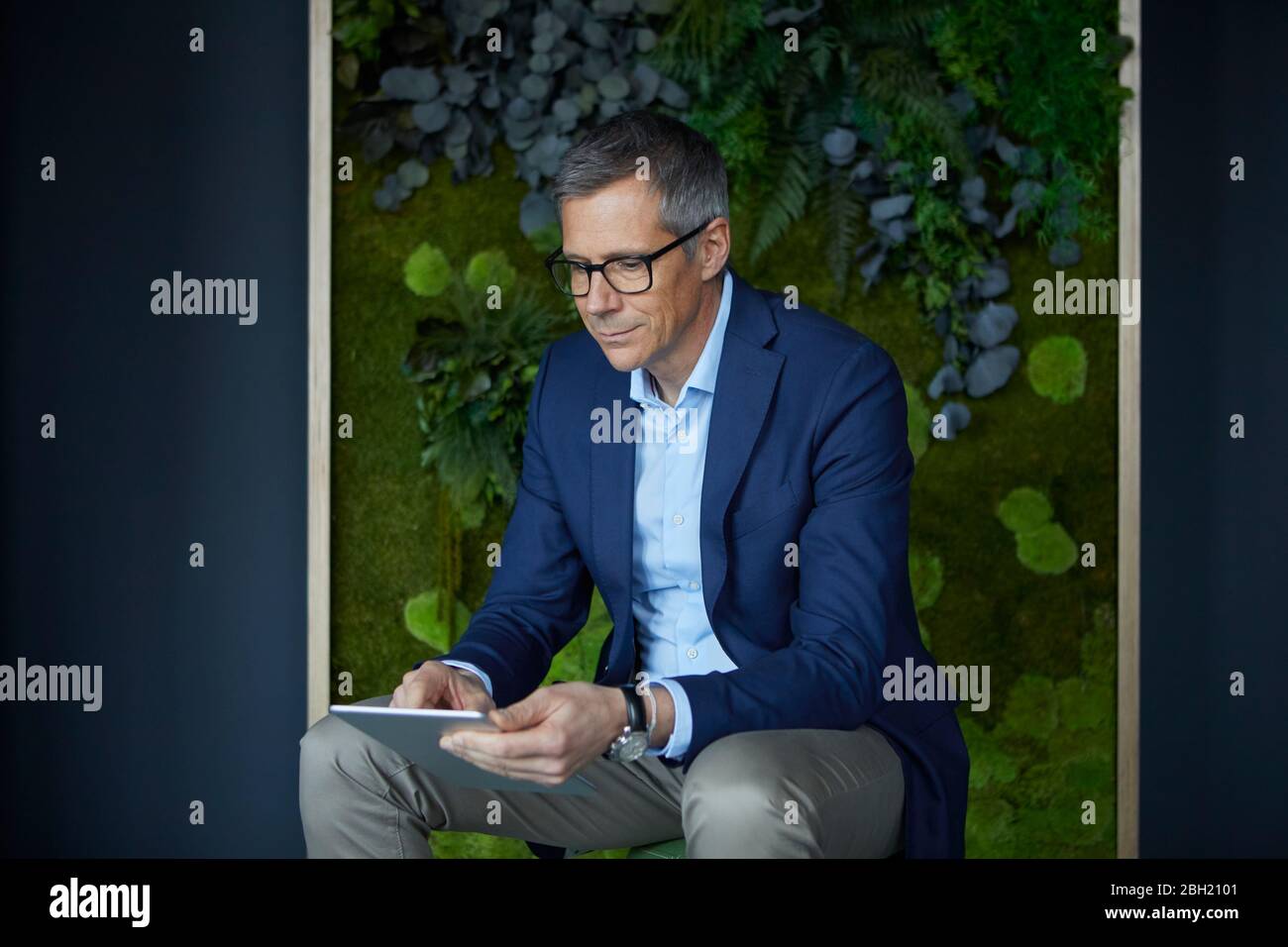 Geschäftsmann mit Tablet im grünen Büro Stockfoto