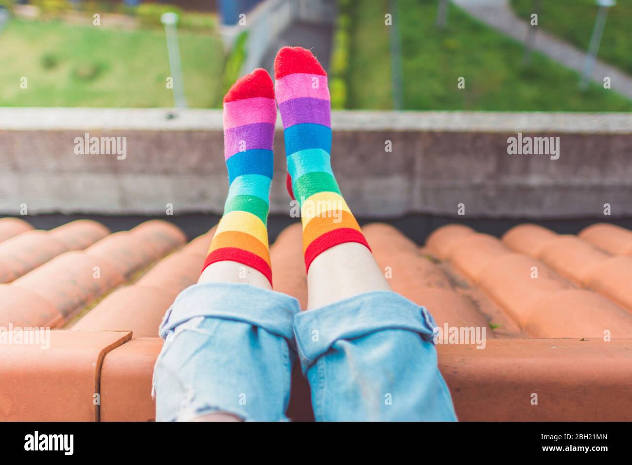 Crop-Ansicht der Frau auf dem Dach sitzen in bunten gestreiften Socken Stockfoto
