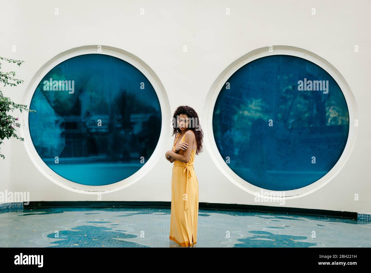 Junge Frau in gelbem Sommerkleid im Pool stehen Stockfoto